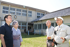 木造校舎の前で伊良波さん（左から２人目）ら