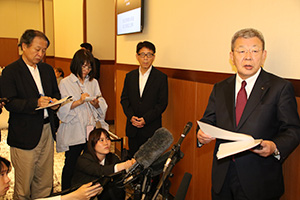 拡大役員会について説明する山下県連幹事長㊨