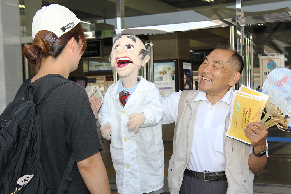 腹話術の人形と共に啓発する会員