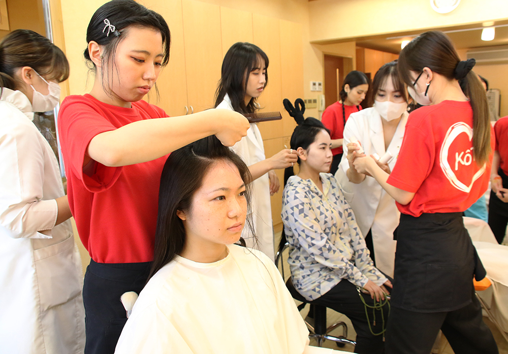 出演者のヘアセットをする学生ら