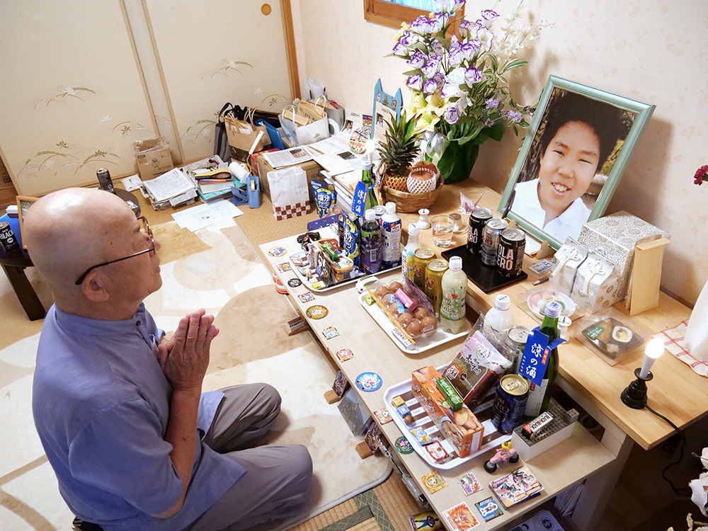 都史さんの遺影に手を合わせる悦雄さん