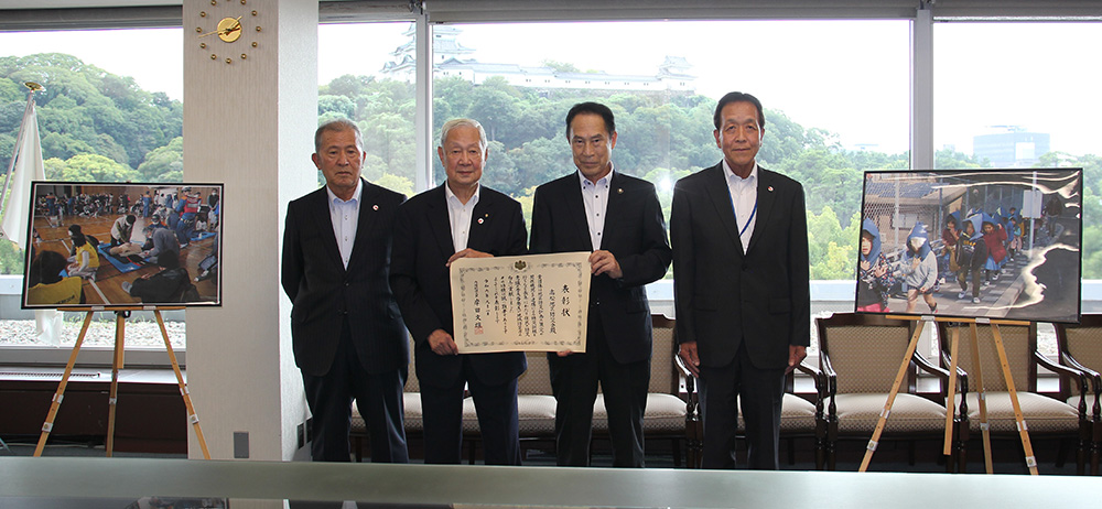 表彰状を手に石井会長（左から２人目）、尾花市長（同３人目）、小泉副会長㊧、前さん