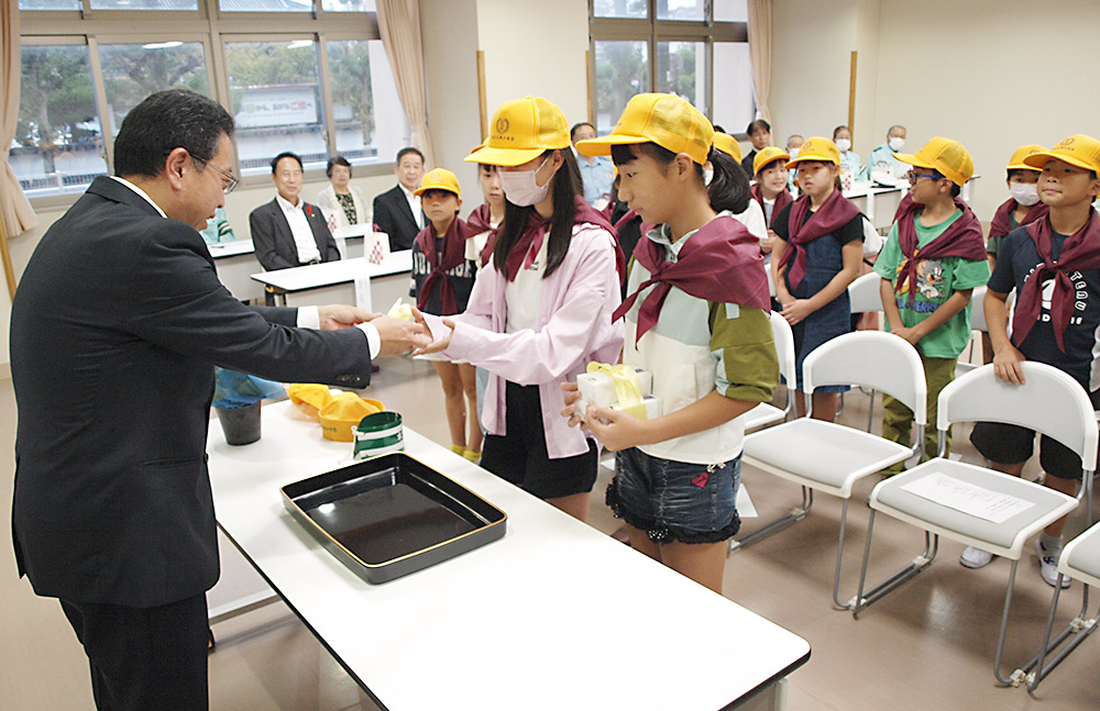 前田団長㊧から寄贈品を受け取る筒井さん（手前）と妙中さん