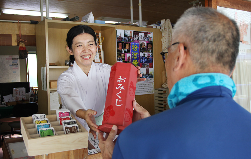 参拝者㊨におみくじを手渡す蒲宮司