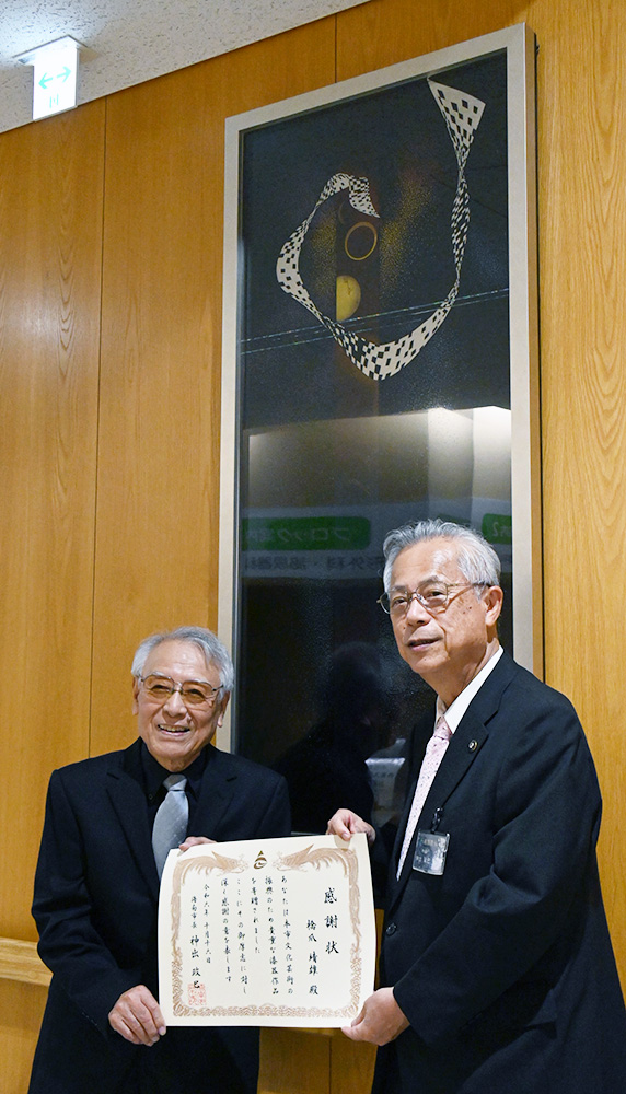 寄贈した作品の前で笑顔の橋爪さん㊧と神出市長