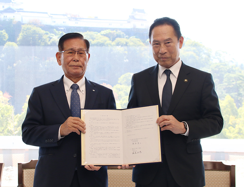 協定書を手に阪本会長㊧と尾花市長