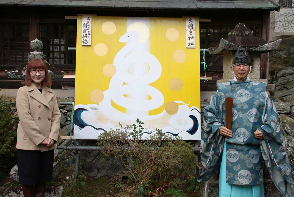 奉納された絵馬の前で若崎さん㊧と山本宮司