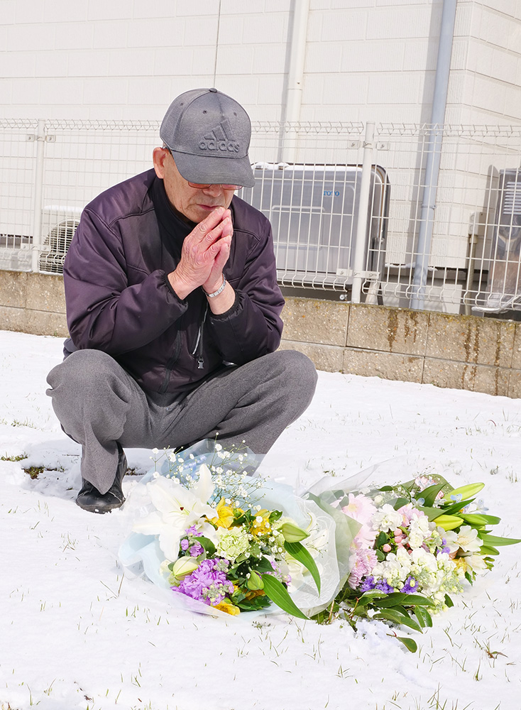 花を供え都史さんの冥福を祈る悦雄さん