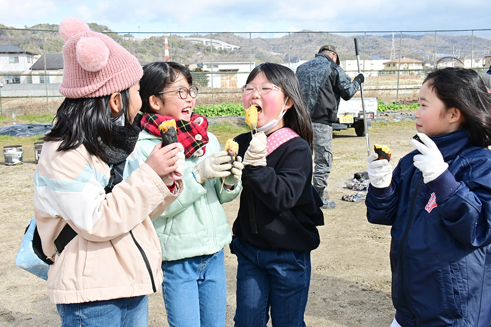 笑顔で焼き芋を頬張る児童たち