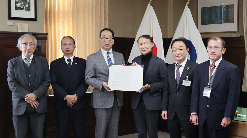 協定書を手にする本山学長（左から３人目）、岸本知事（同４人目）ら