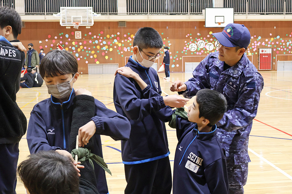 隊員㊨から止血法を教わる生徒たち