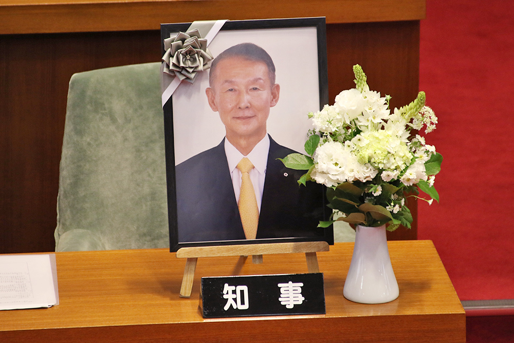 議場の知事席に置かれた岸本前知事の遺影と花