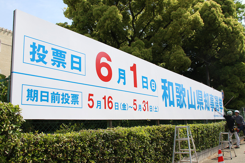 県庁本館前に立て看板を設置する作業員ら