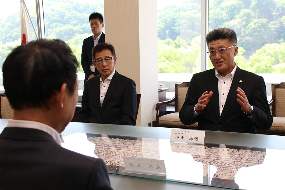 立地協定に調印し、歓談する田中社長㊨と尾花市長(手前)