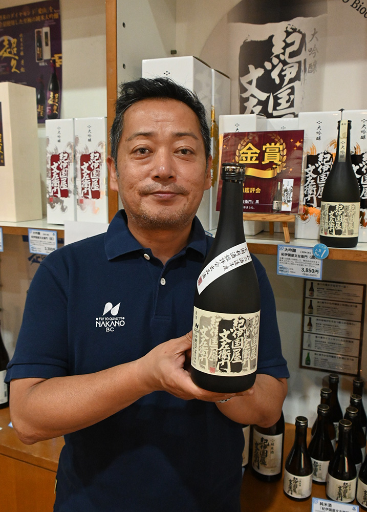 金賞を受けた清酒を手に笑顔の中野代表