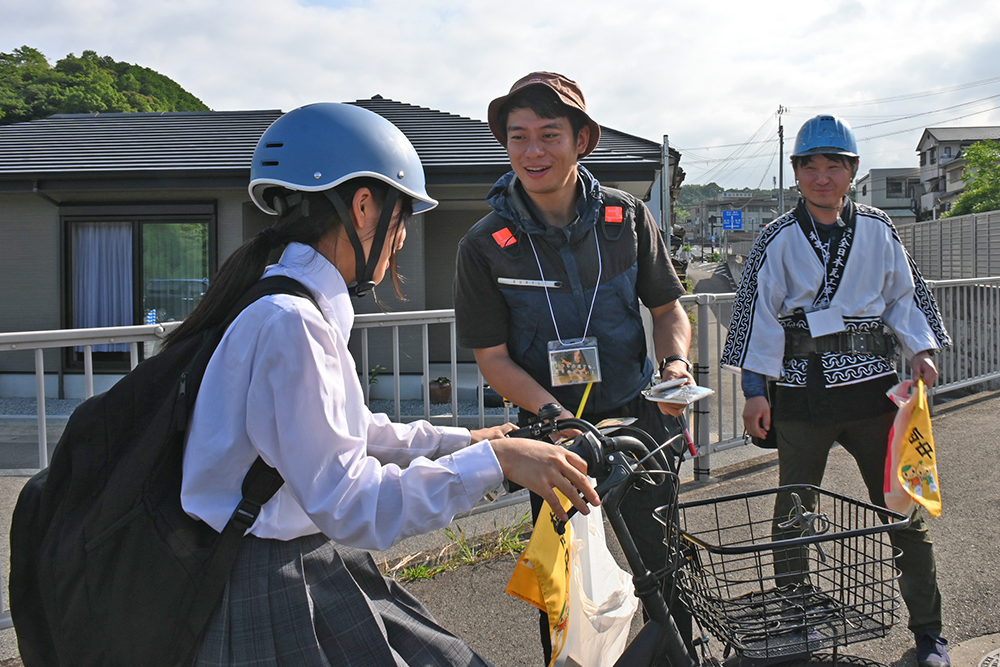 仕事着で配付物を手渡す青年部メンバー