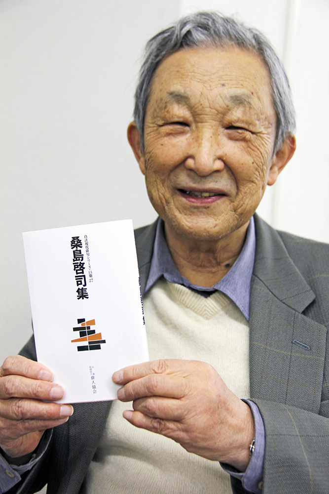 俳句集を手に笑顔の桑島さん