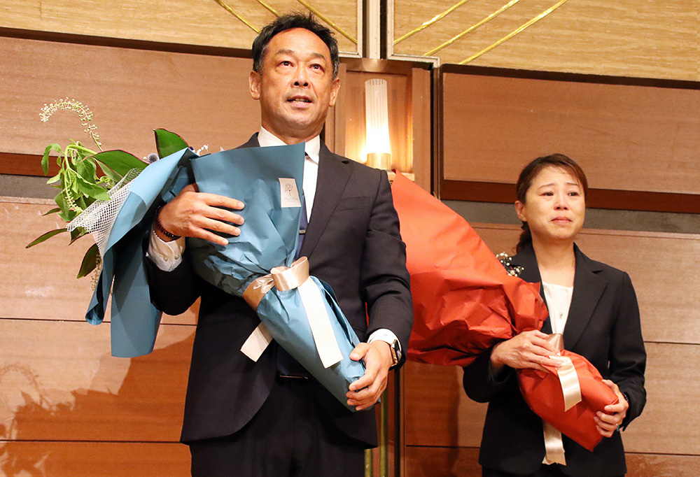 花束を手にする望月さんと㊧と亜紀夫人(午後11時15分)