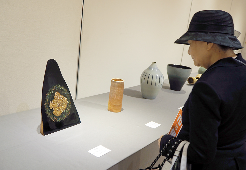 漆絵「おひるね」を鑑賞する来場者