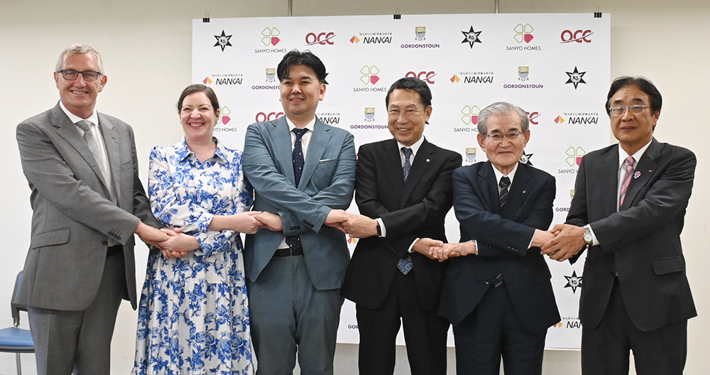 締結式で笑顔の英国本校のラッセル・キュー会長㊧ら