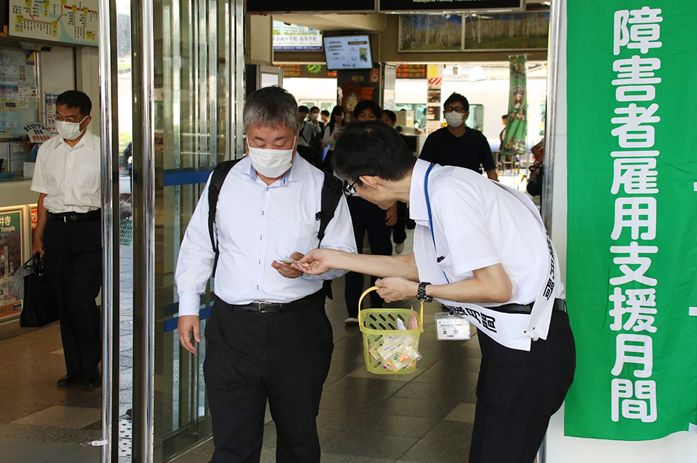 街頭啓発で駅利用者にグッズを手渡す参加者ら(JR和歌山駅前)