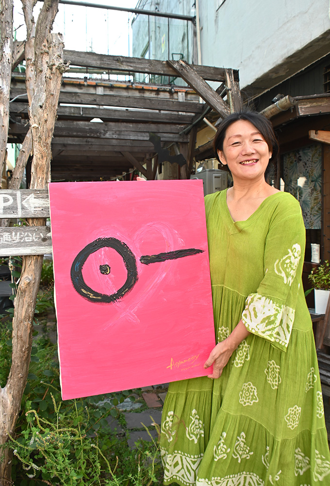 作品を手に笑顔の岡本さん