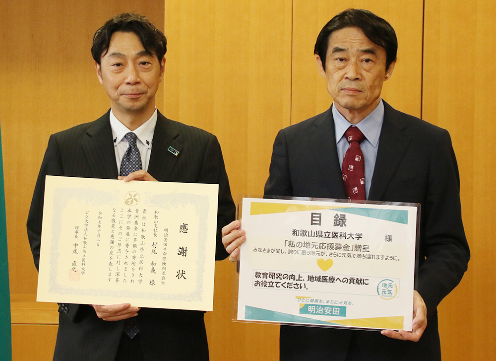 寄付目録と感謝状を手にする村尾支社長㊧、中尾理事長