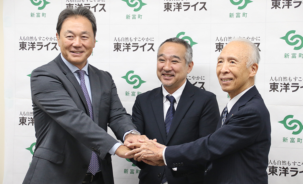 協定を締結し笑顔で握手する（右から）雜賀社長、小嶋町長、清宮副会長