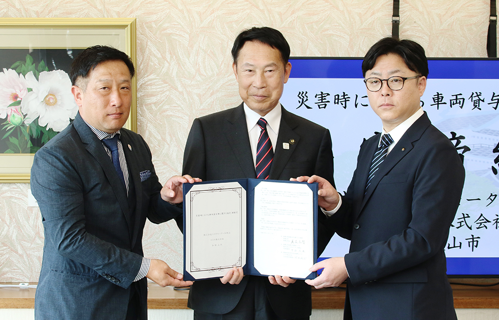 協定書を手に（左から）中谷社長、尾花市長、村木部長