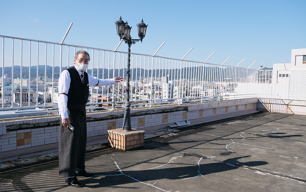 撮影場所近くのテラスを紹介する北田支配人