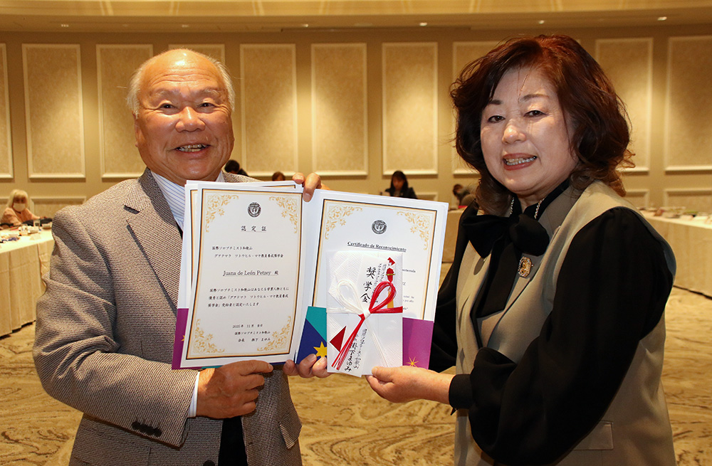 奨学金の認定証と目録を手に掛下会長㊨と宮西名誉教授