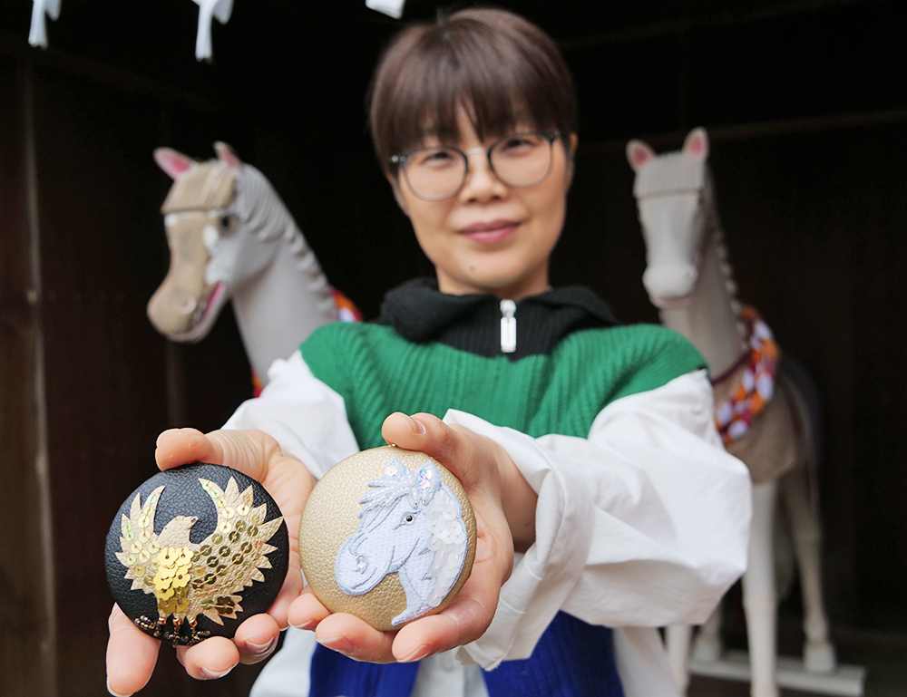 神馬の前でお守りを手にする豊田さん