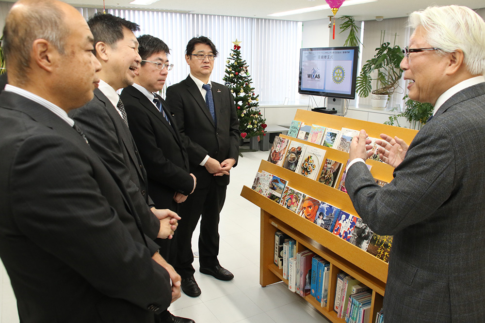 寄贈された本が並ぶ書架の前で談笑