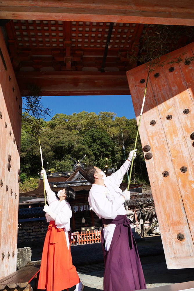 楼門のすす払いをする小板宮司と巫女