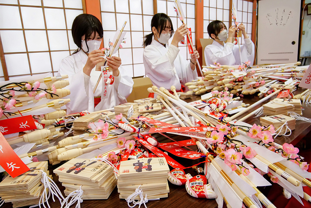 破魔矢に絵馬を結び付ける巫女
