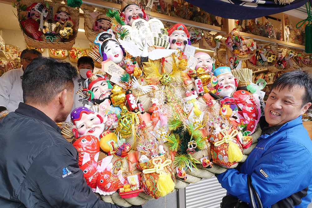 大型の縁起物を受ける参拝者