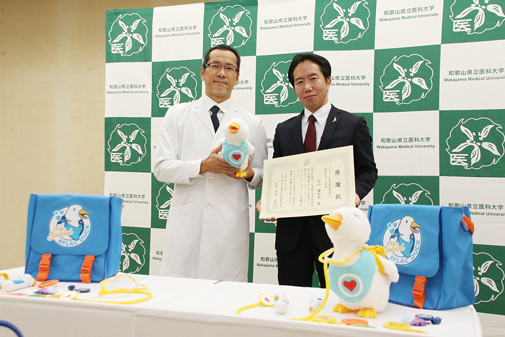 ロボットと感謝状を手に徳原教授㊧と杉山支社長