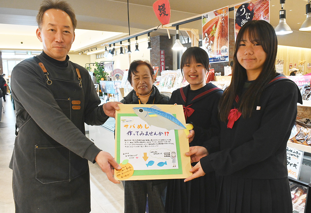さばめしをＰＲした看板を今西店長㊧に手渡す海南高生