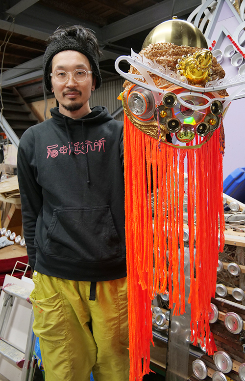 神様の顔の仮面を手に石田さん