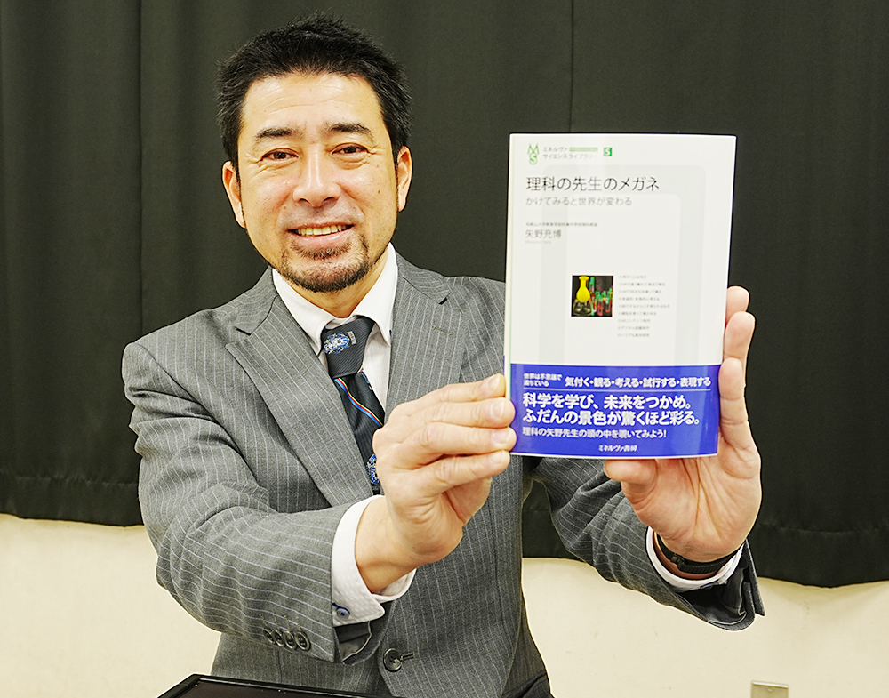 発刊された書籍を手に矢野教諭