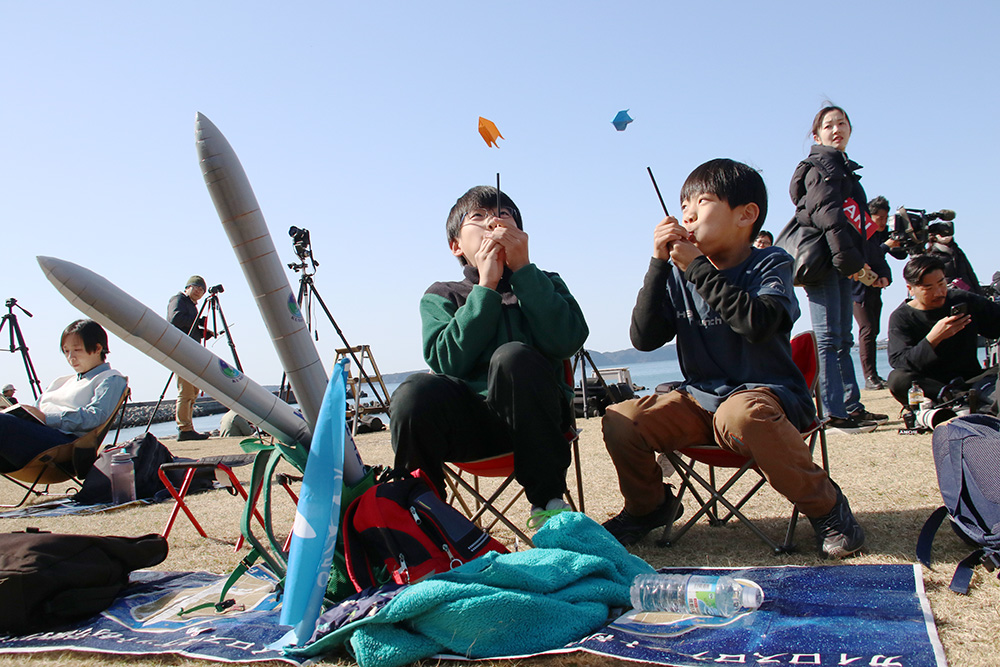 ロケットの折り紙を飛ばしてカイロスを応援する子どもたち