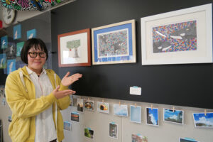 作品を前で笑顔の横田さん