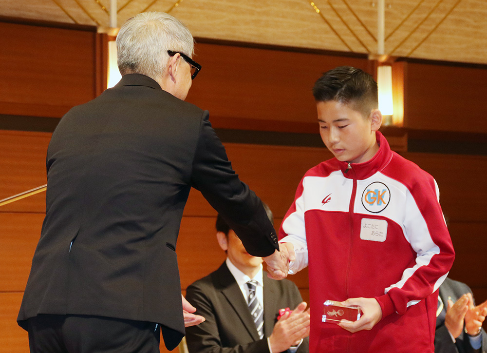 宮﨑知事㊧から記念のクリスタルを受け取る修了生