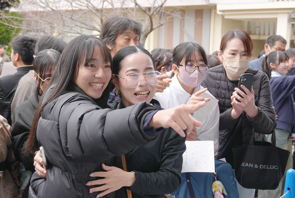 自分の番号を見つけ、家族と抱き合う受験生