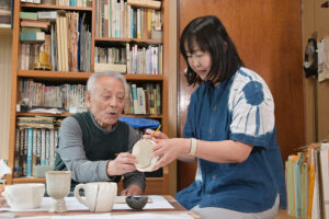 橋爪さん㊧に教わりながら筆で継ぎ目を塗る岩本さん