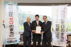 承認書を手に（左から）有田名誉教授、尾花市長、宮下前学長