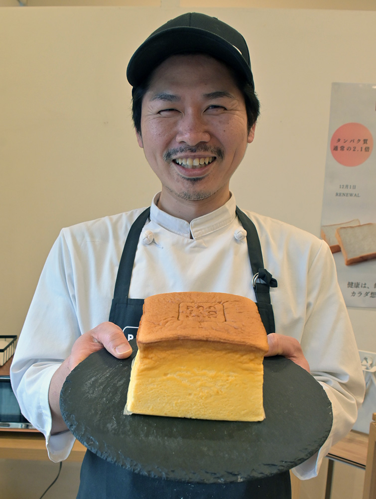 米粉スフレを手に笑顔の佐々木店長