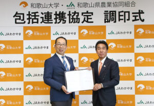 協定書を手にする本山学長㊧と坂東組合長