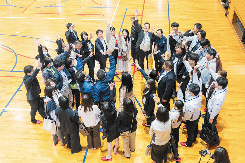 授業当日、円陣を組み心を一つにする「職業先生」や校長、ボランティアスタッフら(山本さん提供)