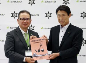 協定プレートを手に角谷社長㊧と尾花市長
